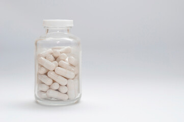closed glass jar with pill capsules on a white background, copy space.