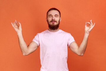 Portrait of bearded man standing with raised arms and doing yoga meditating exercise, mudra...