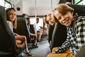 Black driver and multiracial pupils smiling while sitting in school bus