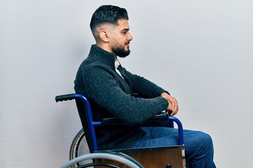 Handsome man with beard sitting on wheelchair looking to side, relax profile pose with natural face...