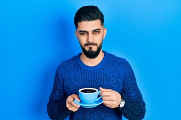 Handsome man with beard drinking a cup of coffee skeptic and nervous, frowning upset because of problem. negative person.