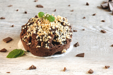 Homemade chocolate cake with nuts and mint leaves on a gray wooden background with chocolate chips. Selective focus with copy space