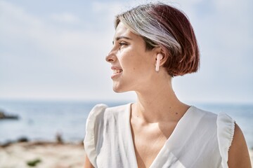 Young caucasian girl smiling happy listening to music at the beach.