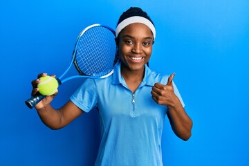 African american woman with braided hair playing tennis holding racket and ball smiling happy and positive, thumb up doing excellent and approval sign - Powered by Adobe
