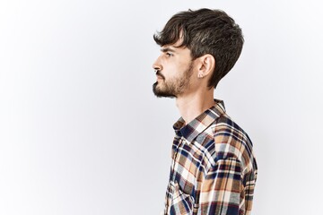 Hispanic man with beard standing over isolated background looking to side, relax profile pose with natural face with confident smile.