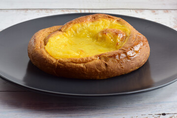 Burnt cream ensaimada, traditional,  served in a plate on a rustic table.