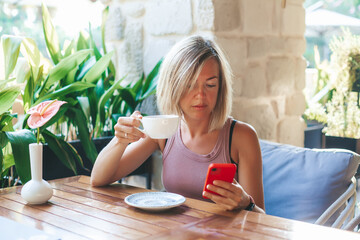 Woman drinking tea holding her mobile phone