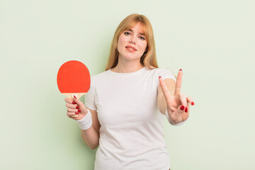 redhead pretty woman smiling and looking happy, gesturing victory or peace. ping pong concept