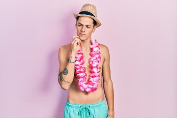 Young hispanic man wearing swimwear and summer hat thinking concentrated about doubt with finger on...