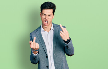 Young hispanic man wearing business clothes showing middle finger doing fuck you bad expression,...