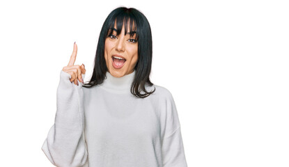 Young brunette woman with bangs wearing casual turtleneck sweater pointing finger up with successful idea. exited and happy. number one.