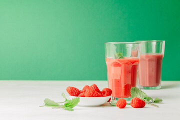 2 glasses with smoothie and drinking straws made of glass. Healthy eating and sustainability. Smoothie made from raspberries and other red fruits. Zero waste and reusable drinking straws made of glass