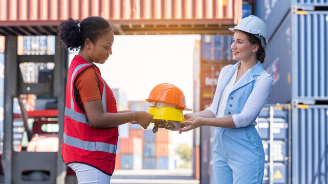 African american woman get safety helmet from Woman CEO cargo container warehouse on activity safety day, assign taske to foreman