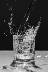Wasserspritzer, Glas beim Befüllen mit Wasser läuft über und spritzt, Studioaufnahme zentriert,...