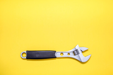 Modern adjustable wrench on a yellow background. The concept of a tool for repair or construction. Special tool for repairing pipes and clamp nuts. Free space for text