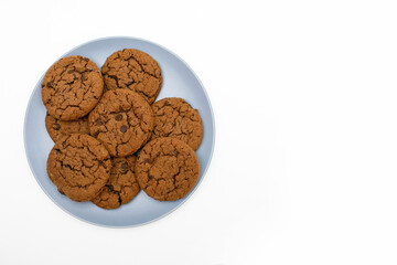 Cookies with chocolate chips lie on a plate on a white background. Sweet homemade chocolate chip cookies. American style breakfast in the form of chocolate chip cookies with free space for text