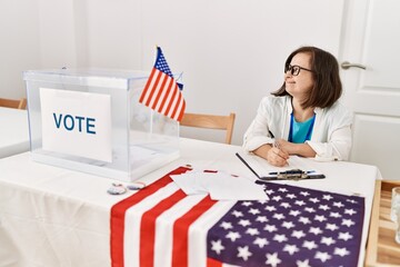 Brunette woman with down syndrome smiling writing on clipboard at election room
