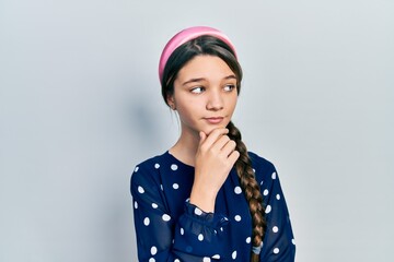 Young brunette girl wearing elegant look with hand on chin thinking about question, pensive expression. smiling with thoughtful face. doubt concept.