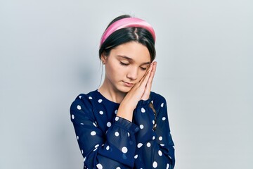 Young brunette girl wearing elegant look sleeping tired dreaming and posing with hands together while smiling with closed eyes.