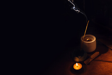 Incense aroma sticks smoldering on table lotus holder and candle in darkness. Zen, meditation, mental health comfort zone