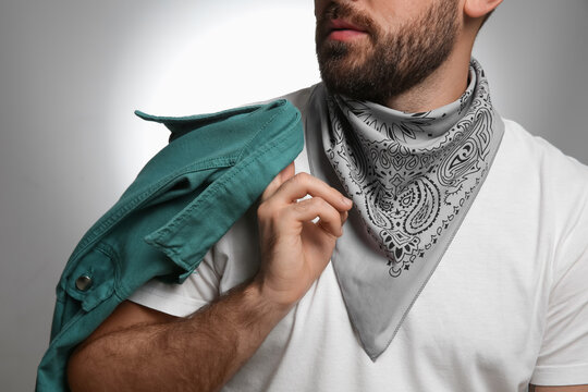 Fashionable young man in stylish outfit with bandana on grey background, closeup