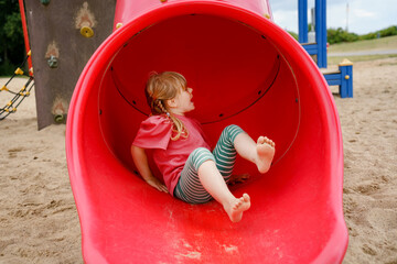 Little preschool girl playing on outdoor playground. Happy toddler child climbing and having fun...