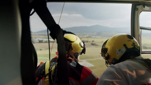 Medical crew with yellow helmet flying in rescue helicopter with open door