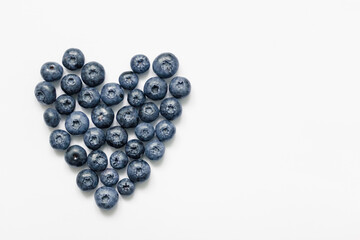 Delicious blueberries formed into a heart shape on white background.