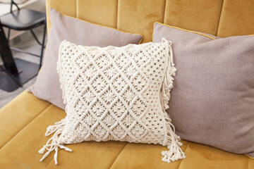 Fototapeta na wymiar Stylish pillow in the interior. Macram decor lifestyle. Eco style. Natural cotton