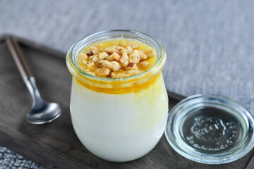 Georgian dessert in a jar decorated with nuts on a wooden board with a spoon
