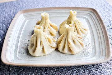 four boiled khinkali on a plate
