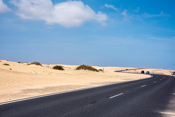 Winding coastal road past sand dunes in Fuerteventura, Canary Islands. 