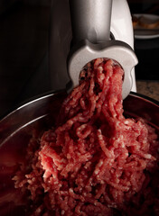 Process of preparing forcemeat by means of a meat grinder. Fresh red mincing close-up on black...
