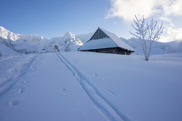 An old hut in a winter landscape with peaks in the background. Gasienicowa Valley. Tatra Mountains.