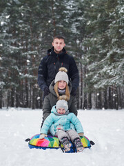 Fototapeta na wymiar Happy family, little daughter and parents. Winter entertainment, tubing