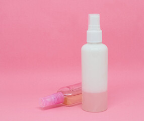 Two spray bottles on a pink background