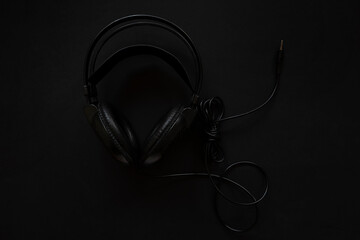 Black headphones on a black background. With cable.