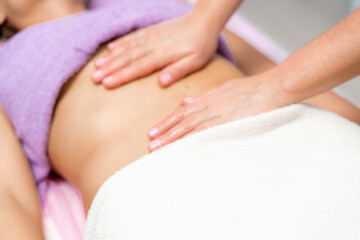 Obraz na płótnie Canvas Top view of hands massaging female abdomen.Therapist applying pressure on belly. Woman receiving massage at spa salon