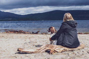 Woman and dog look out over loch in Scotland