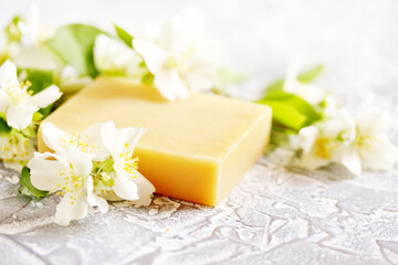 Natural soap with jasmine oil. Ecocosmetics with jasmine extract. Jasmine flowers close-up on a gray background. Selective focus. Space for text,copy space