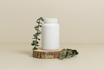 Mockup medical bottle for pills or vitamins with eucalyptus leaves on wooden podium, bio...