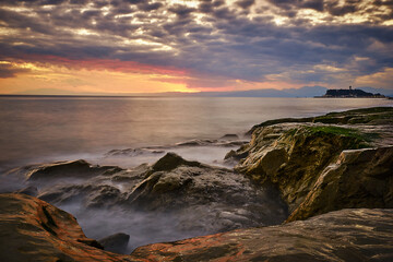A slow shutter shot of waves crashing on a rocky beach.