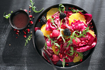 Salad with radish and fresh fruits on dark table. Detox food. Top view with copy space.