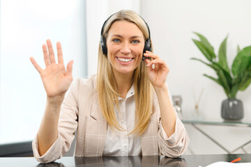 Headshot of smiling young female employee wearing wireless headset, looking at the camera, Cheerful...