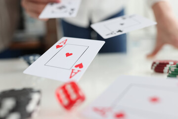Playing cards aces and dice flying over gaming table in casino closeup