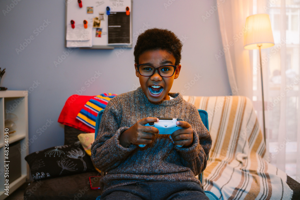 Wall mural Black boy screaming while using joystick while playing online game