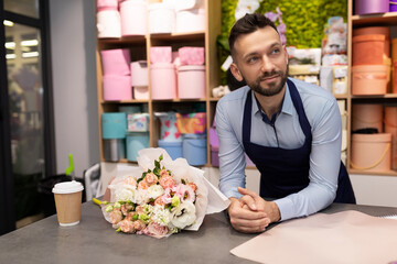 tired florist smiling looking at camera next to bouquet of flowers