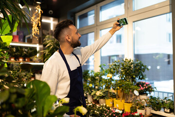 flower shop worker taking selfie among potted plants