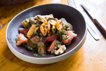 Tomatoes with arugula pesto and mussels served on a plate