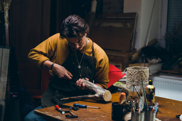 man sitting in his workshop and making artwork from wood